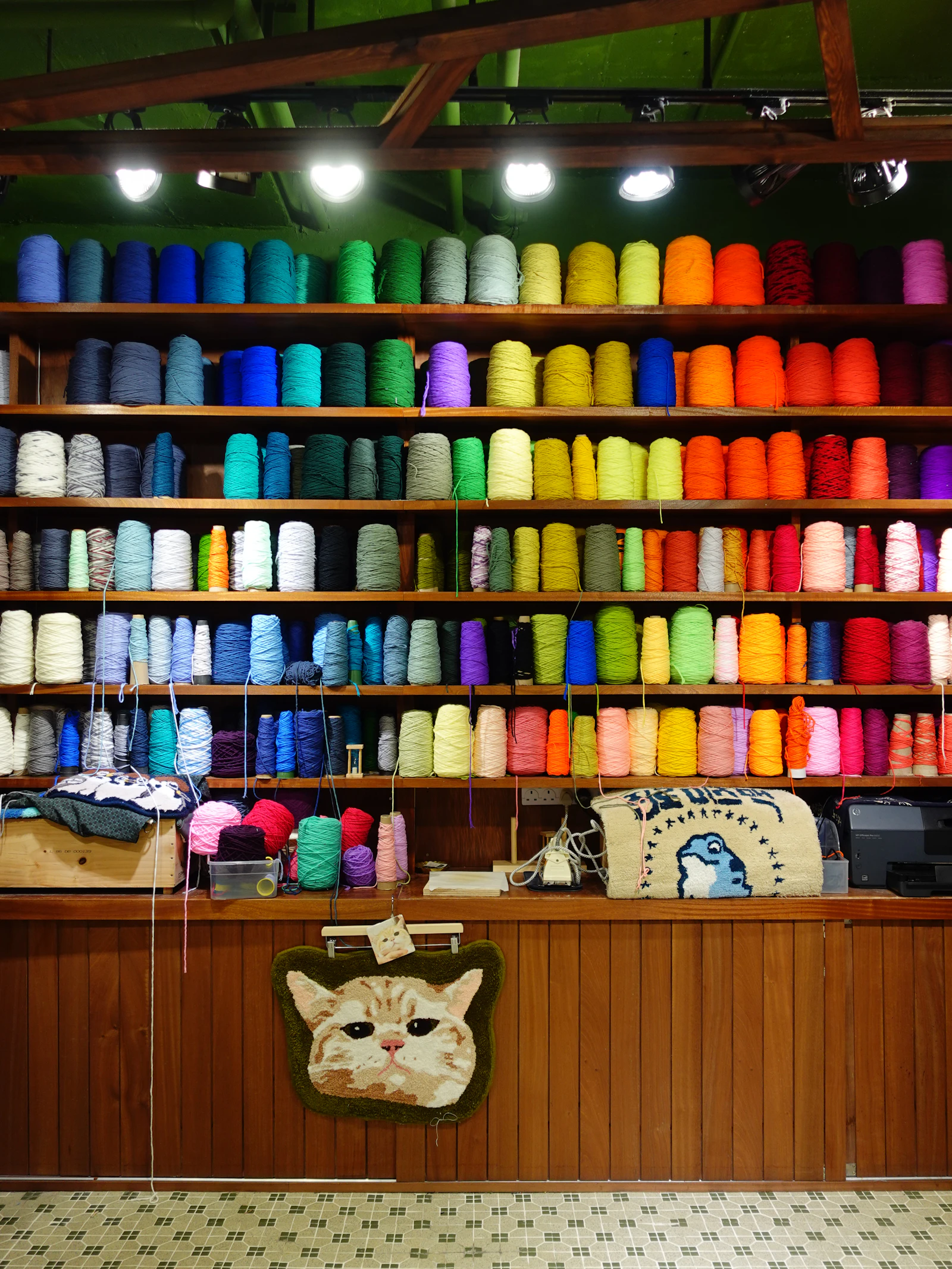 Étagères d'atelier remplies de bobines de fil colorées rangées par teintes