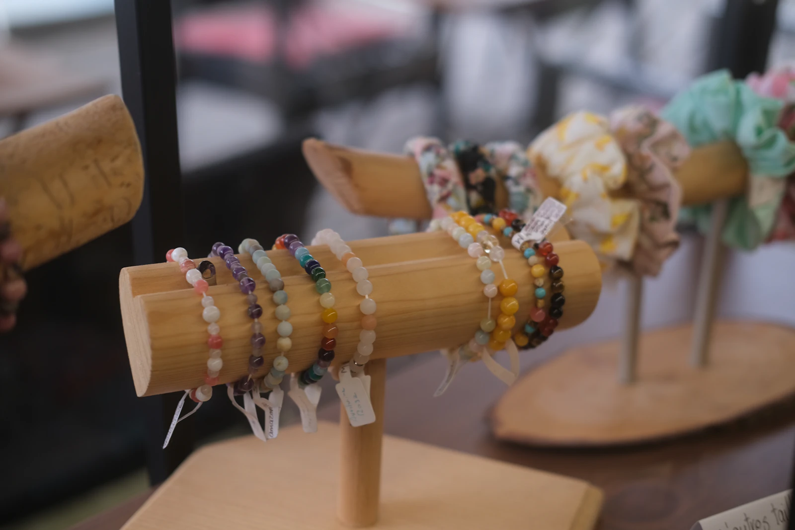 Bracelets artisanaux disposés sur un présentoir en bois, prêts pour un marché de créateurs